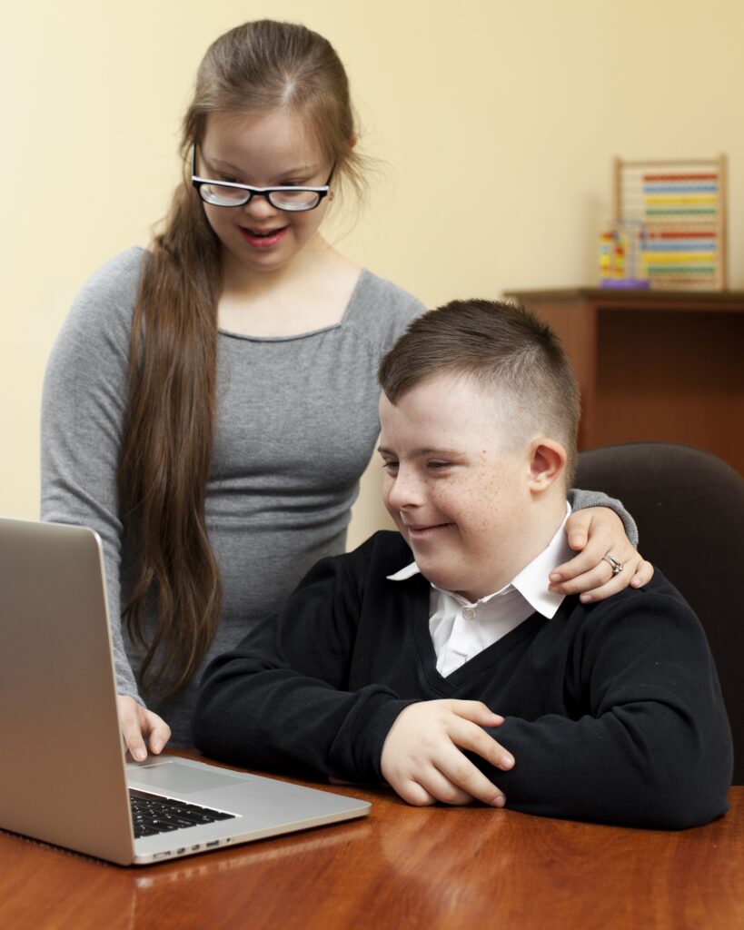Zwei junge Menschen mit Beeinträchtigung arbeiten zusammen an einem Computer