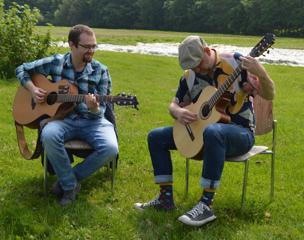 Fest & frei spielen Gitarre auf einer Wiese
